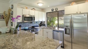 Una cocina moderna con encimeras de granito, electrodomésticos de acero inoxidable y armarios blancos.