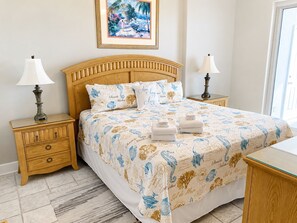 A hotel room with a wooden bed, two bedside tables with lamps, a framed picture on the wall, and a view of the outside.