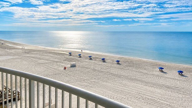 Een strand met een heldere lucht, een zandstrand en enkele parasols.