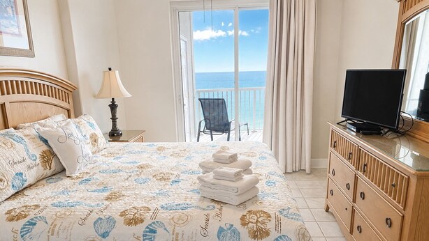 Una camera da letto con un letto, una TV, un comò e vista sul mare.