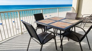 Een balkon met een tafel en stoelen, met uitzicht op een strand.