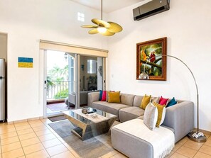 Una sala de estar con un sofá, una mesa de centro, un cuadro y un ventilador de techo.