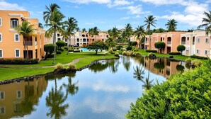 A resort with a swimming pool, palm trees, and buildings with balconies. - Resort Villa w/ Lake Views, Pool & Walk to Beach (Humacao)