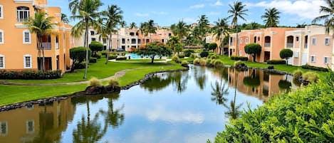 A resort with a swimming pool, palm trees, and buildings with balconies.