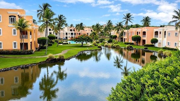 A resort with a swimming pool, palm trees, and buildings with balconies.
