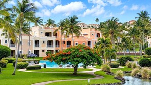 A resort with a swimming pool, palm trees, and a well-maintained lawn. - Resort Villa w/ Lake Views, Pool & Walk to Beach (Humacao)