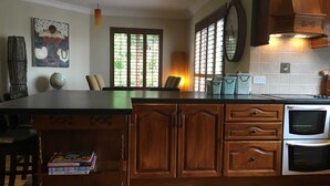 A kitchen with wooden cabinets, a central island, a stove, and a dining area with chairs and a table.