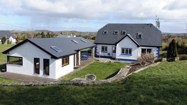 A two-story house with a sloped roof, a stone foundation, and a small attached garage.