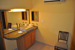 A bathroom with a double sink, a large mirror, and a chair. - Loft Penthouse w/ terrace, WIFI, grill, 3min walk to beach, few blocks to dwtn (Cabo San Lucas)