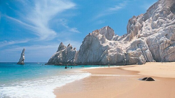A beach with clear turquoise waters, rocky cliffs, and a sandy shore. - Loft Penthouse w/ terrace, WIFI, grill,  3min walk to beach, few blocks to dwtn (Cabo San Lucas)