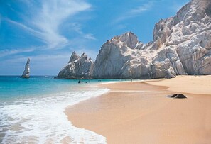 Een strand met helder turquoise water, rotsachtige kliffen en een zandstrand.