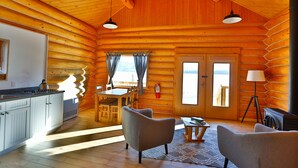 A log cabin interior with a kitchen, dining area, and two seating areas. - Southern Lakes Resort (Tagish)