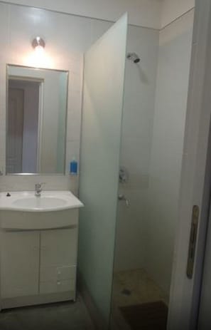 A bathroom with a white sink, mirror, and glass shower enclosure.