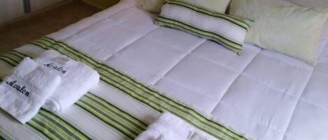 A neatly made bed with striped bedding and two towels labeled "Avalon".