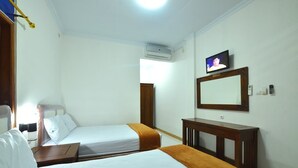 A hotel room with two beds, a TV, a mirror, and a desk. - Hotel Bukit Uhud Yogyakarta (Yogyakarta)
