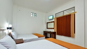 A hotel room with two single beds, a small table, a television, and a window with curtains. - Hotel Bukit Uhud Yogyakarta (Yogyakarta)