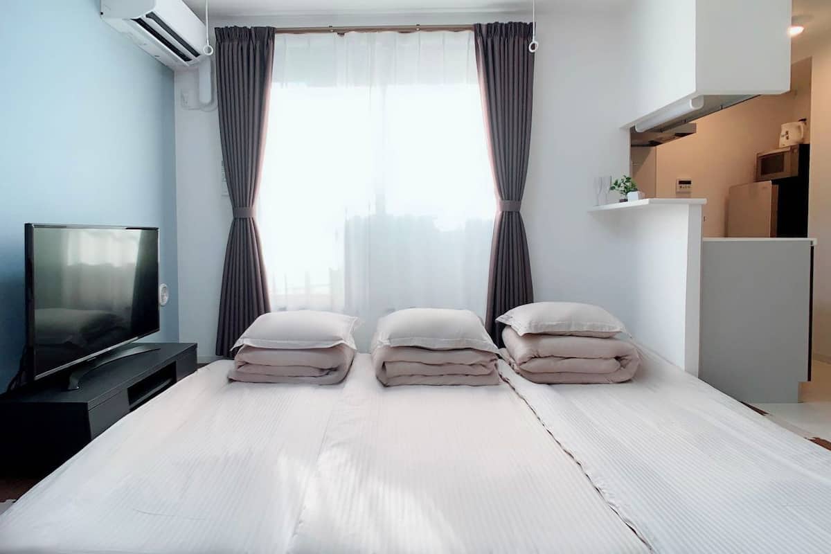 Una habitación de hotel moderna con cama, televisión y kitchenette.