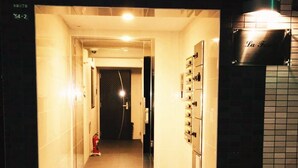 En hotellkorridor med en brandsläckare, ett kaklat golv och en skylt som är monterad på väggen.