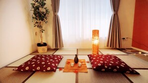Ett traditionellt japanskt rum med tatamimattor, en shojiskärm, en hängande växt och en dekorativ lampa.