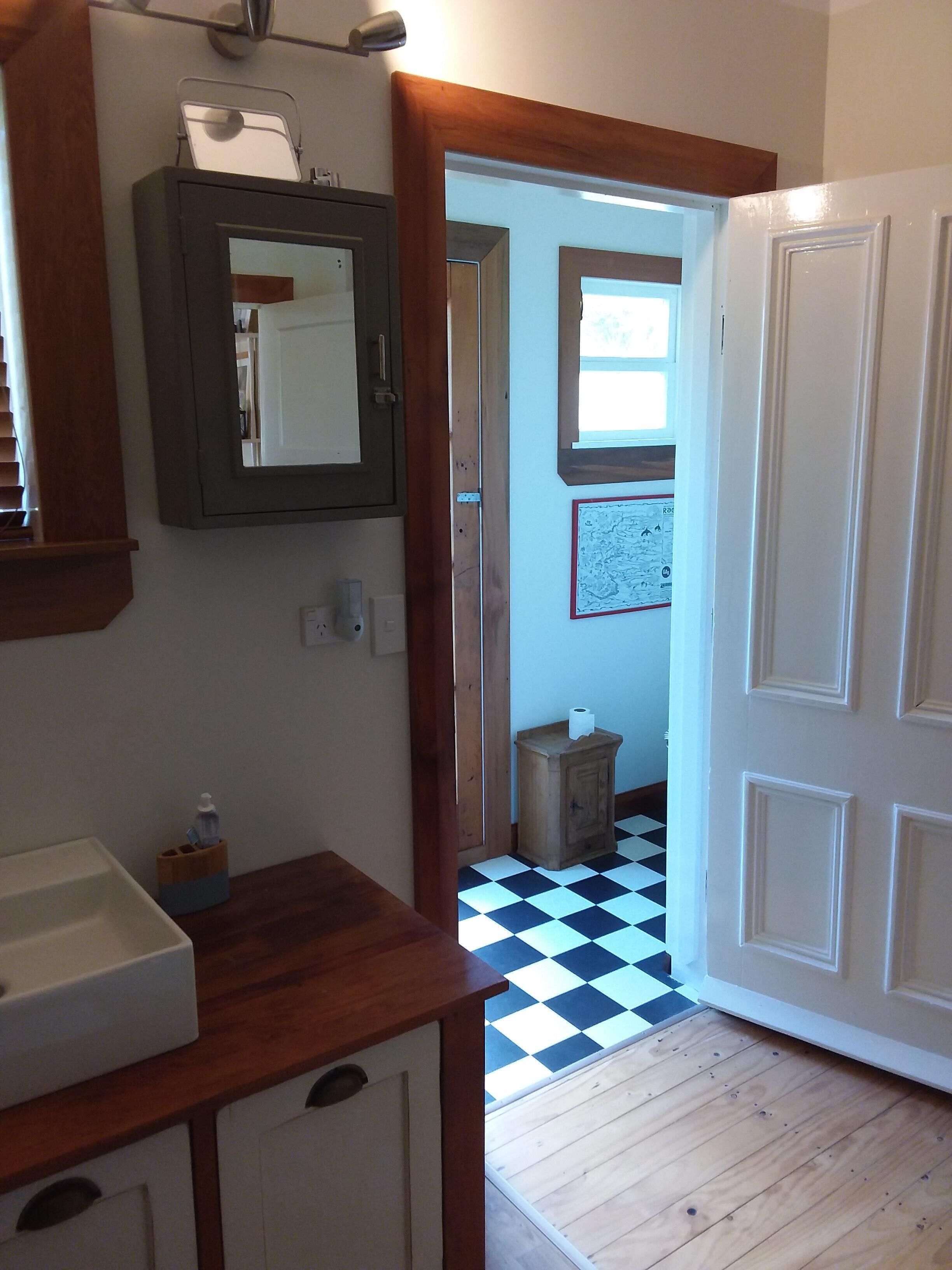 Une salle de bain avec un meuble-lavabo en bois, un miroir et un petit placard.