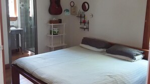 A bedroom with a wooden bed, a guitar, a small shelf with toys, and a mirror on the wall. - Raglan west at its best (Raglan)