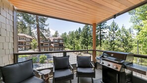 A balcony with a grill and two chairs, overlooking a residential area with trees and buildings. - Steps to Heavenly, Lake & More | Tahoe Woods #101 (South Lake Tahoe)