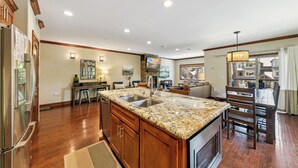 A spacious kitchen with granite countertops, wooden cabinets, and a large island with a sink. - Steps to Heavenly, Lake & More | Tahoe Woods #101 (South Lake Tahoe)