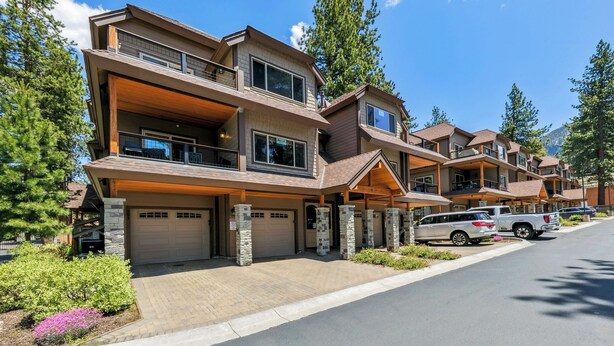 A multi-story residential building with a garage, stone pillars, and a driveway with parked cars. - Steps to Heavenly, Lake & More | Tahoe Woods #101 (South Lake Tahoe)