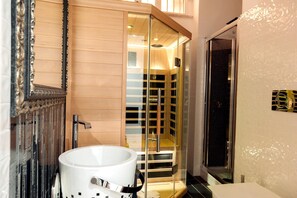 Une salle de bain moderne avec une douche à parois de verre, un lavabo blanc et un grand miroir doté d’un cadre orné.