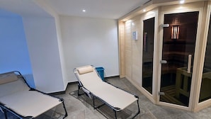 A room with a massage table, a glass door closet, and a blue trash bin. - Residence Seeblick 14 with lateral Baltic Sea view - Studio beach shell / with (Sellin)