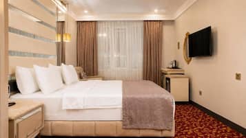 A hotel room with a bed, bedside tables, a television, and a window with curtains.
