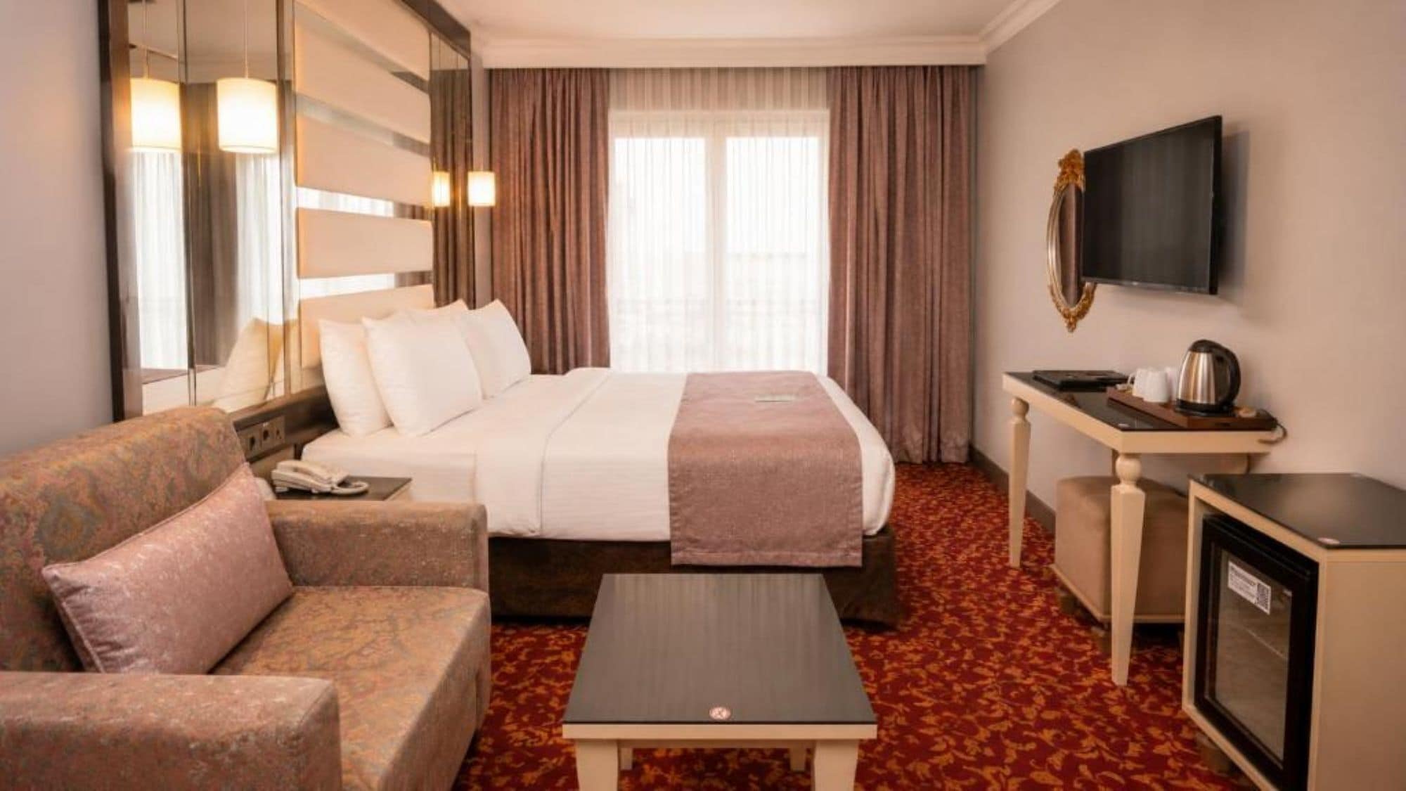 Une chambre d’hôtel équipée d’un lit, d’un canapé, d’un bureau, d’une télévision et d’une machine à café.