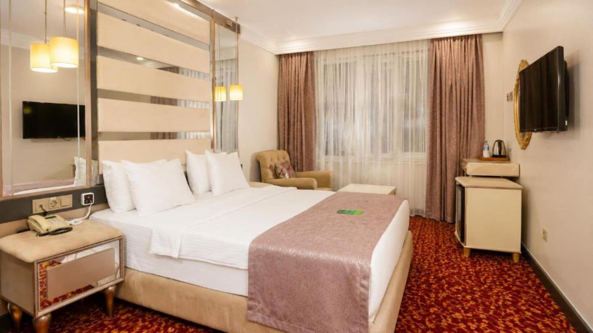 Une chambre d’hôtel comprenant un lit, une table de chevet, une chaise et un téléviseur.