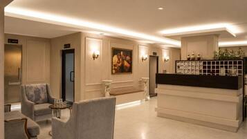 Un hall de hotel con asientos, una recepción y un cuadro en la pared.