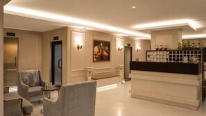 A hotel lobby with seating, a reception desk, and a painting on the wall.