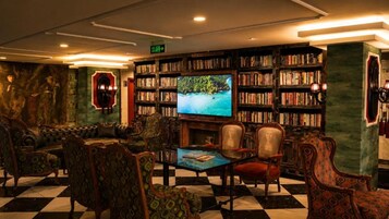 A library with bookshelves, a television, and comfortable seating.