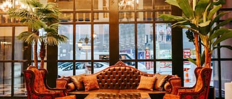 A lobby with a checkered floor, a tufted sofa, and two patterned armchairs.