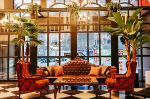 A lobby with a checkered floor, a tufted sofa, and two patterned armchairs.