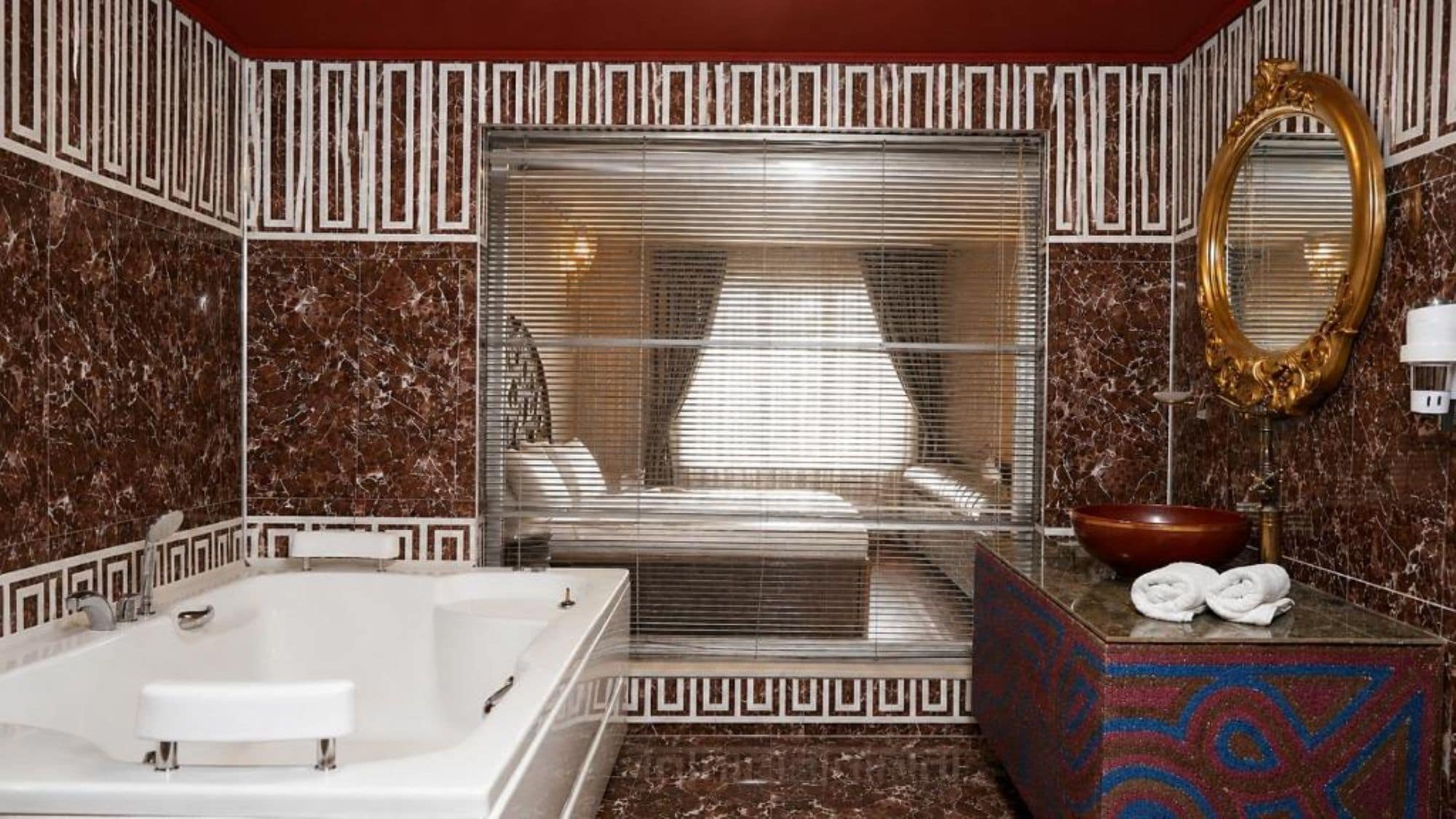 A bathroom with a large bathtub, a mirror, and a sink with a bowl.