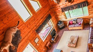 Interno di una baita di legno con camino, mobili in legno e corna di cervo alle pareti.