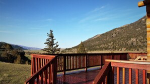 Una terrazza in legno con ringhiera che si affaccia su un paesaggio montuoso.