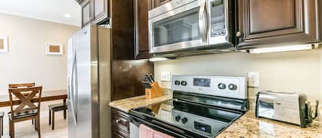 Una cocina con un refrigerador de acero inoxidable, dos hornos, un microondas y un tostador.