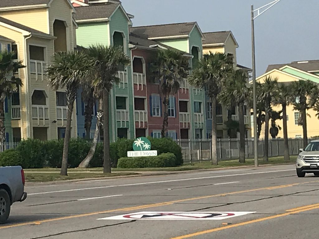 Een hotel met meerdere verdiepingen, balkons en palmbomen.