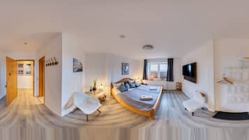 Un dormitorio moderno con una cama grande, un área de descanso y un televisor.