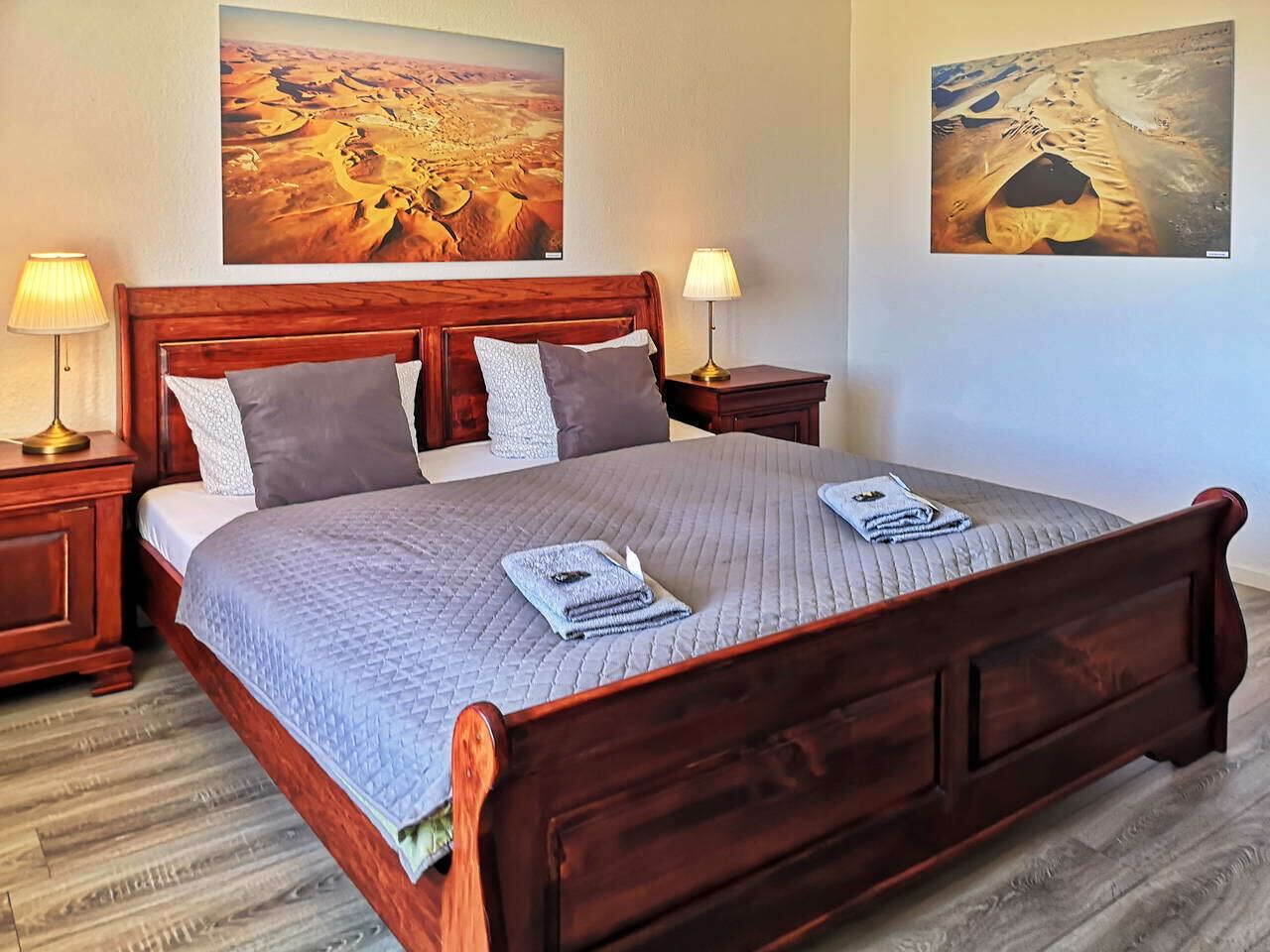 A double bed with a quilted bedspread, two bedside lamps, and two pillows.