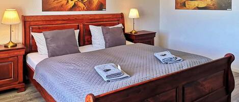 A double bed with a quilted bedspread, two bedside lamps, and two pillows.