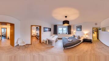 Een moderne slaapkamer met een groot bed, nachtkastjes, een bureau en een stoel. Er is een raam met gordijnen en een plafondlamp.