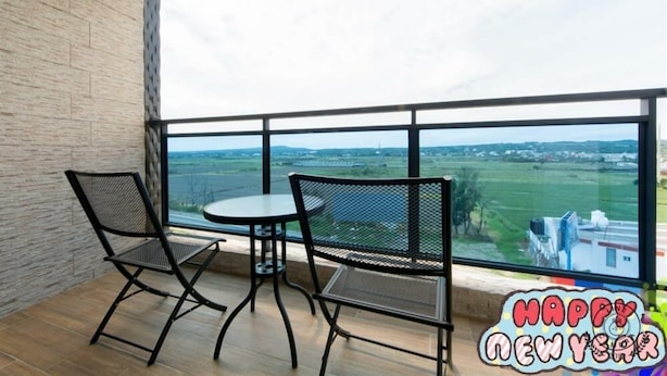 Uma varanda com duas cadeiras e uma mesa, com vista para uma paisagem deslumbrante.