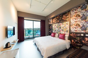 Habitación de hotel con una cama grande, televisión, escritorio y balcón con vistas.