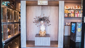 Exposição de uma estátua com design intrincado, rodeada por vitrines com diversos objetos.